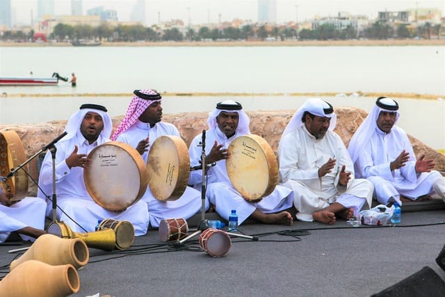 Musiciens traditionnels au Bahreïn jouant des percussions près de la mer, illustrant la richesse culturelle d’un voyage au Bahreïn – voyage sur mesure avec Nahra Travel, spécialiste Asie et Moyen-Orient.